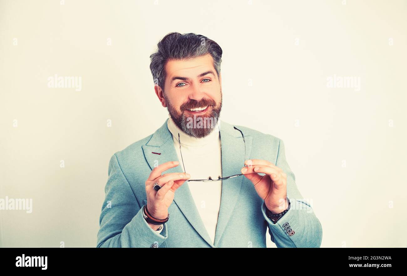 Fröhlicher Geschäftsmann, der freundlich und lächelnd ist, während er eine Brille und einen modernen blauen Anzug trägt. Stockfoto