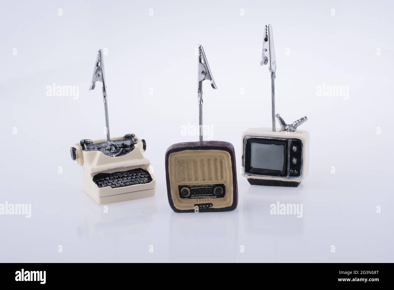 Retro-Modell mit winzigen Fernsehern, Radio und Schreibmaschine auf weißem Hintergrund Stockfoto