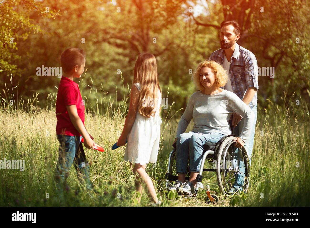 Lächelnde Kinder spielen mit ihren behinderten Jungen Mutter Stockfoto