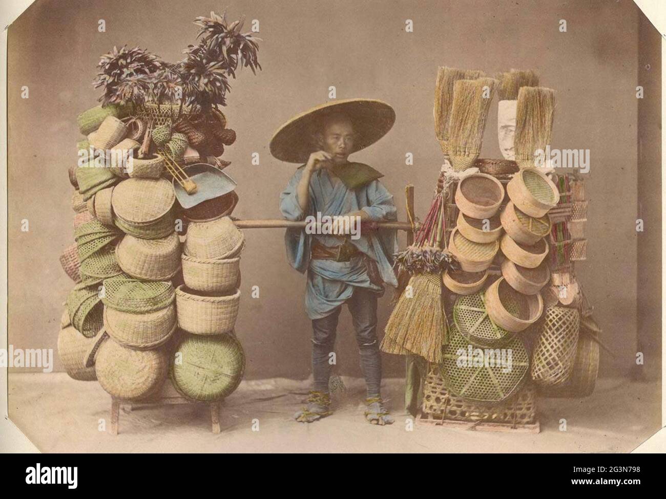 Alte Kusakabe Kimbei Fotografie aus dem alten Japan. Ein Korbverkäufer in traditioneller Kleidung mit seinen Körben zum Verkauf. Stockfoto