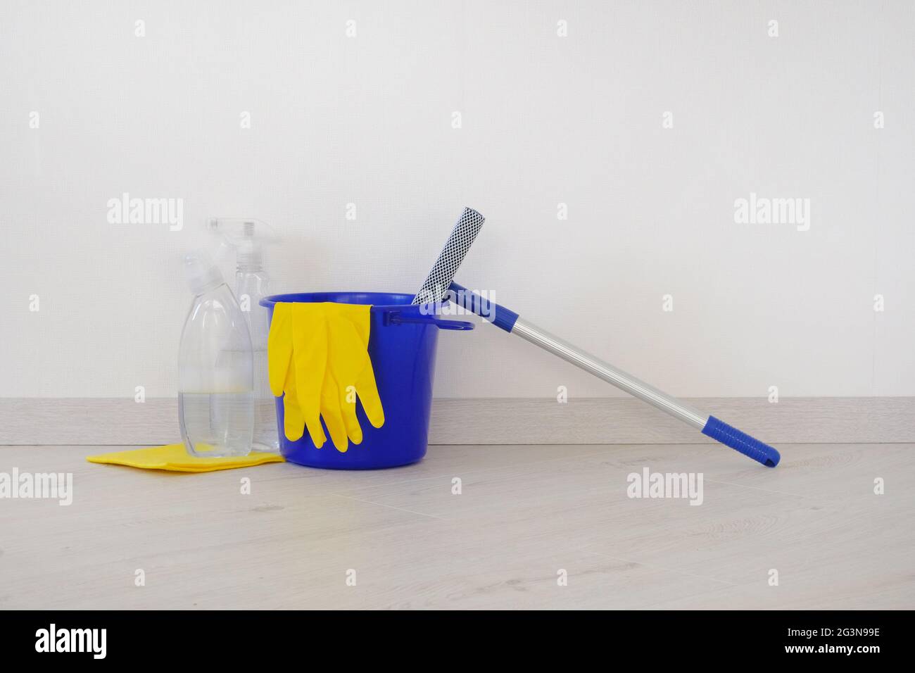 Reinigungskonzept. Eimer mit Waschflüssigkeiten, Gummischutzhandschuh und blauem Mopp. Stockfoto Reinigungskonzept. Eimer mit Waschflüssigkeiten, Gummischutzhandschuh und blauem Mopp. Stockfoto
