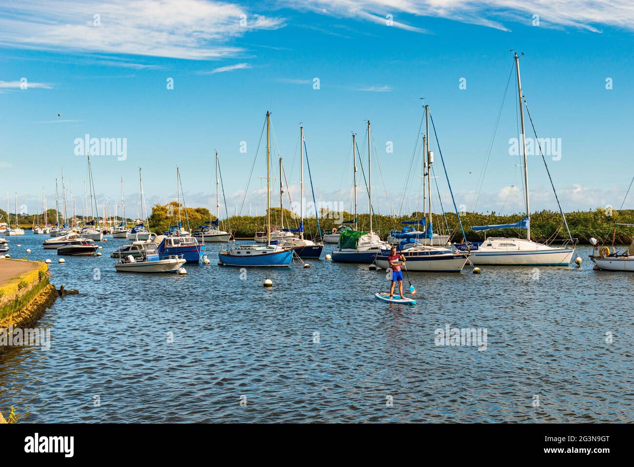 Mann auf einem Paddelbrett inmitten kleiner Boote im Hafen von Christchurch, Dorset Stockfoto