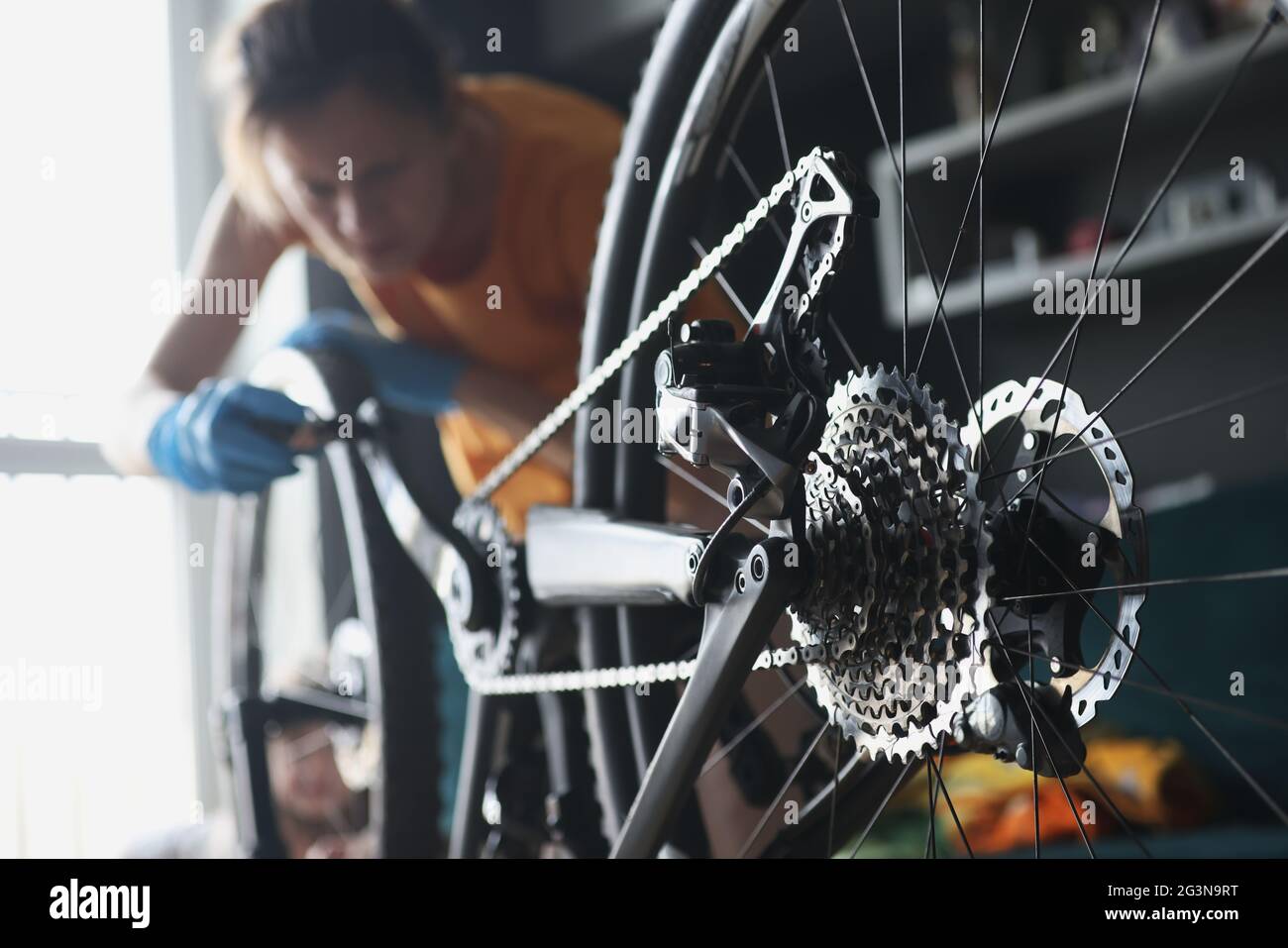 Frau Werkstatt in Gummihandschuhen Reparatur Fahrrad mit Werkzeugen Nahaufnahme Stockfoto
