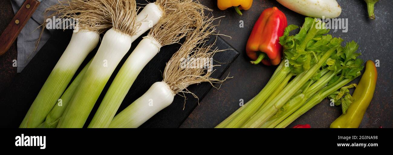 Lauch, Auberginen, Paprika, Sellerie und Petersilie auf dunklem Betongrund. Selektiver Fokus.Draufsicht. Speicherplatz kopieren. Stockfoto