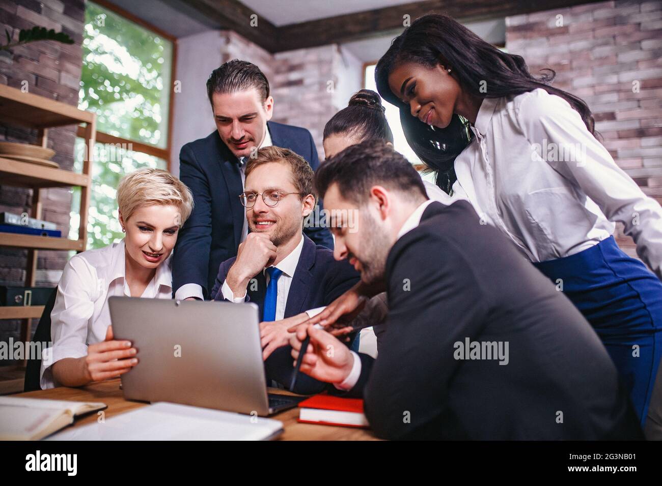 Happy Hochschulen sammeln sich um Laptop im Büro Stockfoto