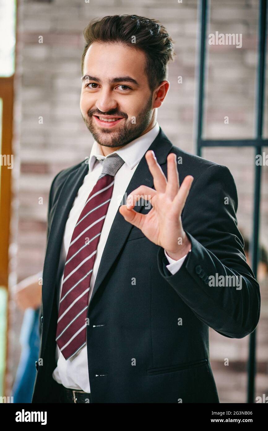 Gut aussehender Geschäftsmann zeigt ein ok Geste. Porträt Stockfoto