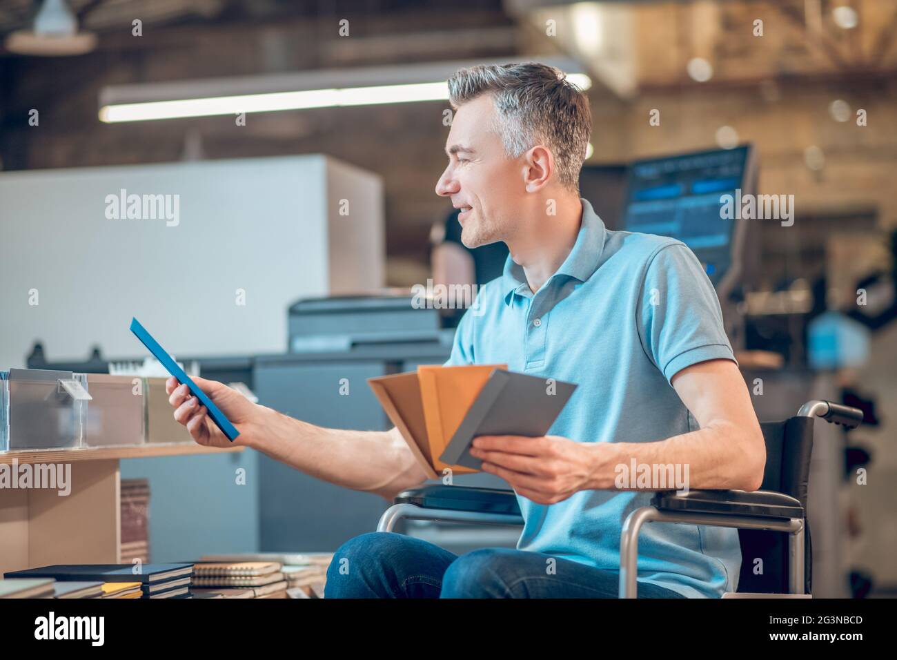 Profil eines Mannes im Rollstuhl, der Briefumschlag wählt Stockfoto