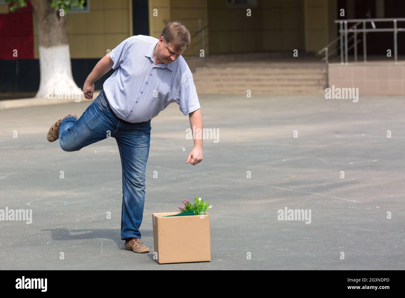 Erzürnter Mann kicks Box mit persönlichen Habseligkeiten nach der Entlassung. Stockfoto