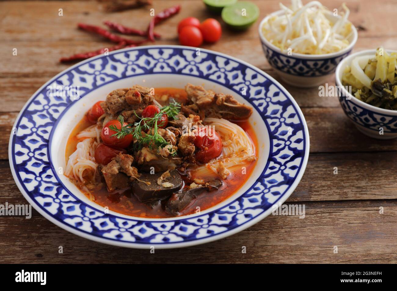 Lokale nordthailändische Küche Reisnudeln mit Schweinefleisch in würzigen Suppe im Holzhintergrund Stockfoto