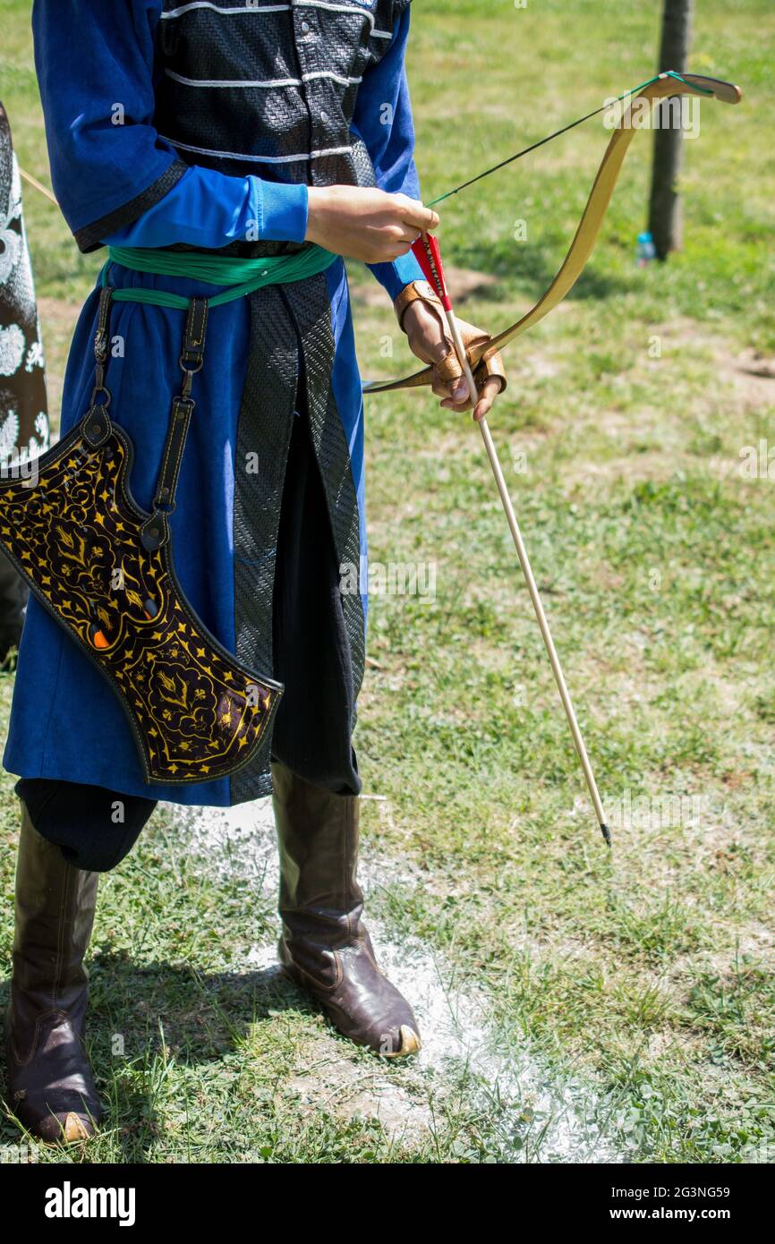 Bogenschütze in traditioneller Kleidung, die einen Pfeil schießt Stockfoto
