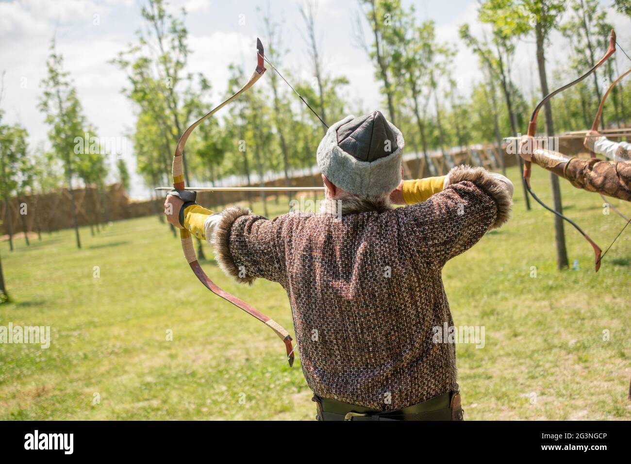 Bogenschütze in traditioneller Kleidung, die einen Pfeil schießt Stockfoto