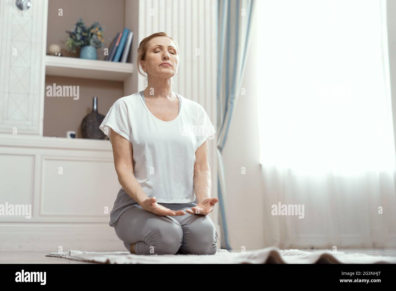 Attraktive reife Frau praktiziert Yoga in Frieden Stockfoto