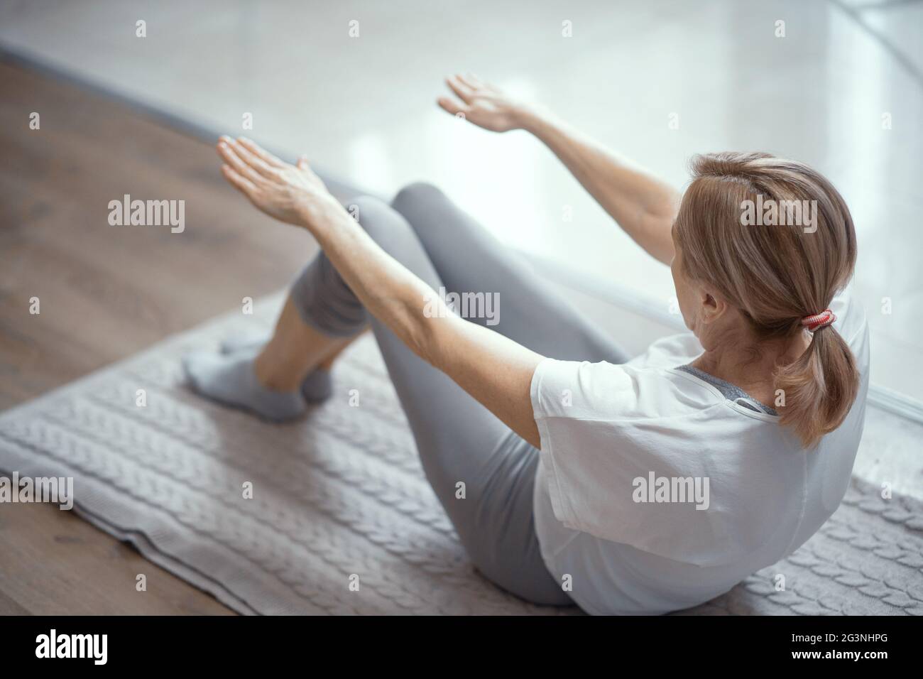 Ziemlich reife Frau streckt ihre Beine und Arme. Rückansicht Stockfoto