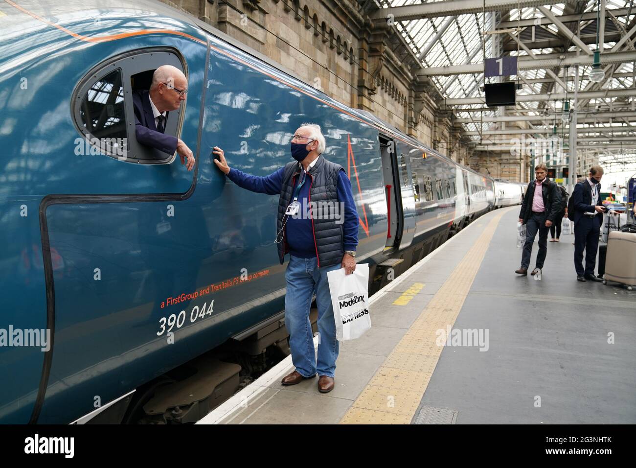 Zugfan Pete Waterman spricht mit dem Zugfahrer Neil Barker an Bord des Avanti Westküsten-Emu-Zuges der Klasse 390, der von London Euston aus den 36 Jahre alten Rekord für die schnellste Zugfahrt zwischen London und Glasgow nicht gebrochen hat. Der Royal Scot-Zug erreichte Glasgow Central 21 Sekunden hinter dem Rekord von drei Stunden, 52 Minuten und 40 Sekunden, den British Rail im Dezember 1984 aufgestellt hatte.Bilddatum: Donnerstag, 17. Juni 2021. Stockfoto