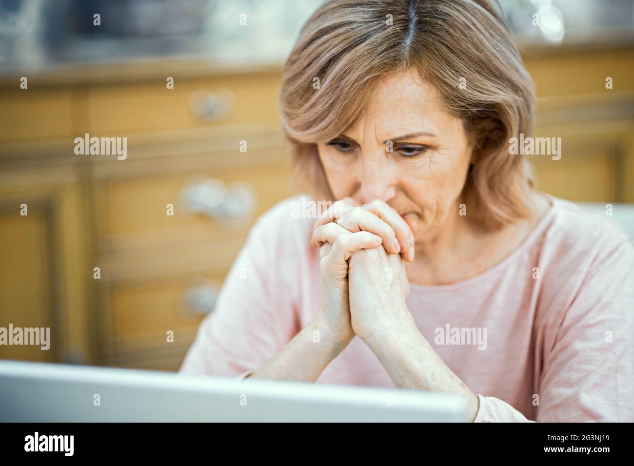 Geballte Frau starrt pensiv in den Laptop Stockfoto