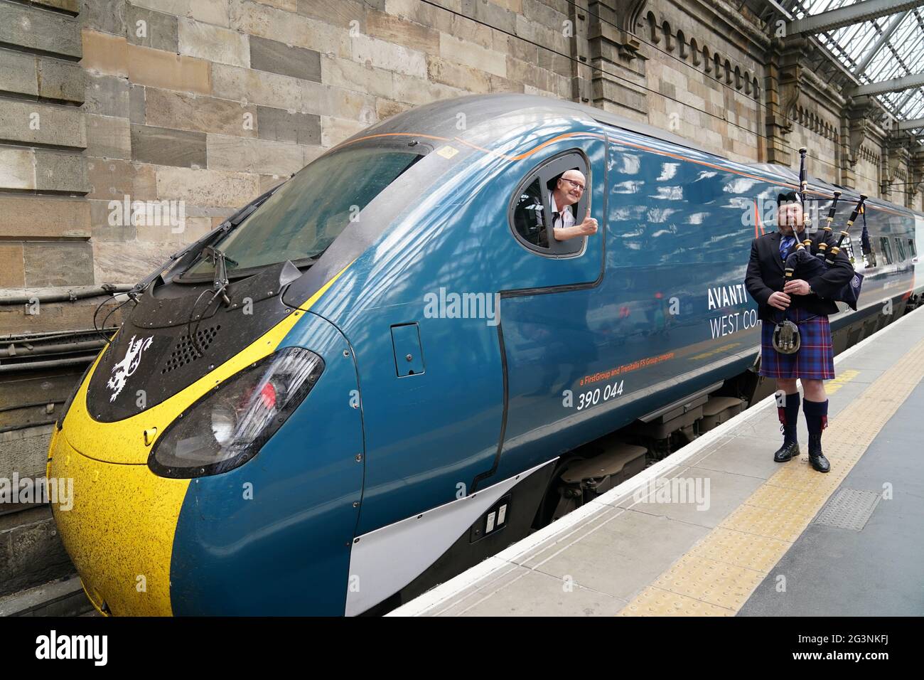 Ein Piper spielt, während Zugfahrer Neil Barker an Bord des Avanti-Westküsten-Emu-Zuges der Klasse 390 Daumen nach oben zeigt, der von London Euston aus am Hauptbahnhof von Glasgow angekommen ist, nachdem er den 36 Jahre alten Rekord für die schnellste Zugfahrt zwischen London und Glasgow nicht gebrochen hat. Der Royal Scot-Zug erreichte Glasgow Central 21 Sekunden hinter dem Rekord von drei Stunden, 52 Minuten und 40 Sekunden, den British Rail im Dezember 1984 aufgestellt hatte.Bilddatum: Donnerstag, 17. Juni 2021. Stockfoto