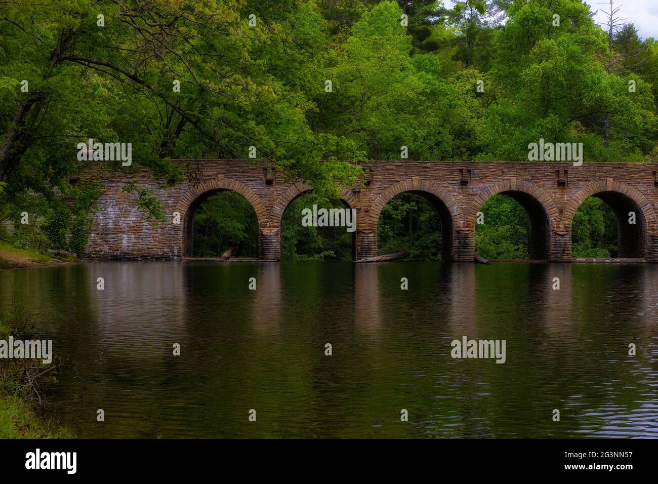 Eine Steinbrücke und ein Staudamm sorgen für eine Überquerung des Wassers im Cumberland Mountain State Park in Tennessee, USA Stockfoto