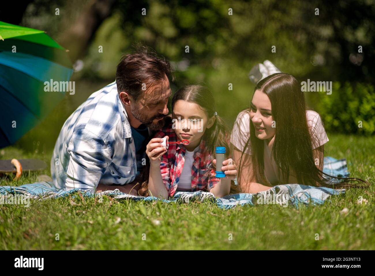 Familie liegen auf der Decke im Park. Tochter Holding Seifenblasen. Stockfoto