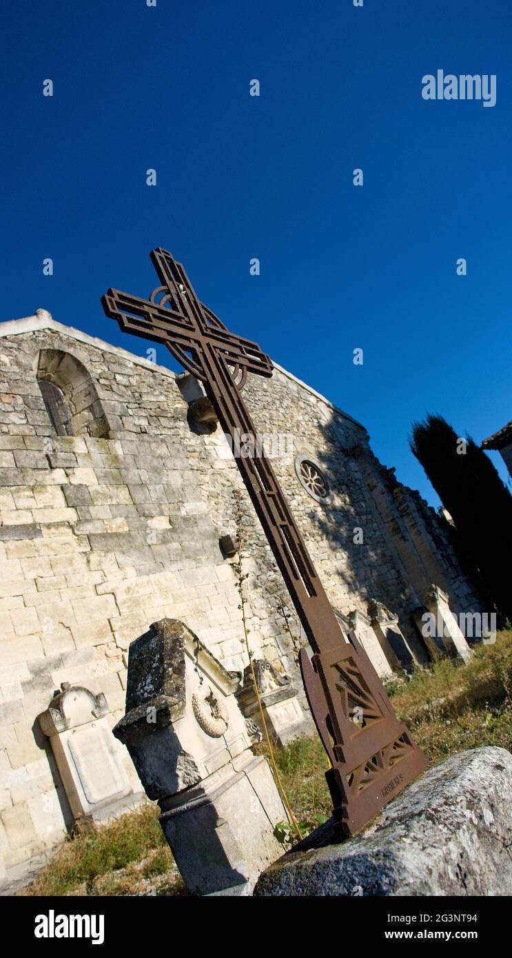 Steinkreuz und Grabsteine vor der Kirchenmauer Stockfoto