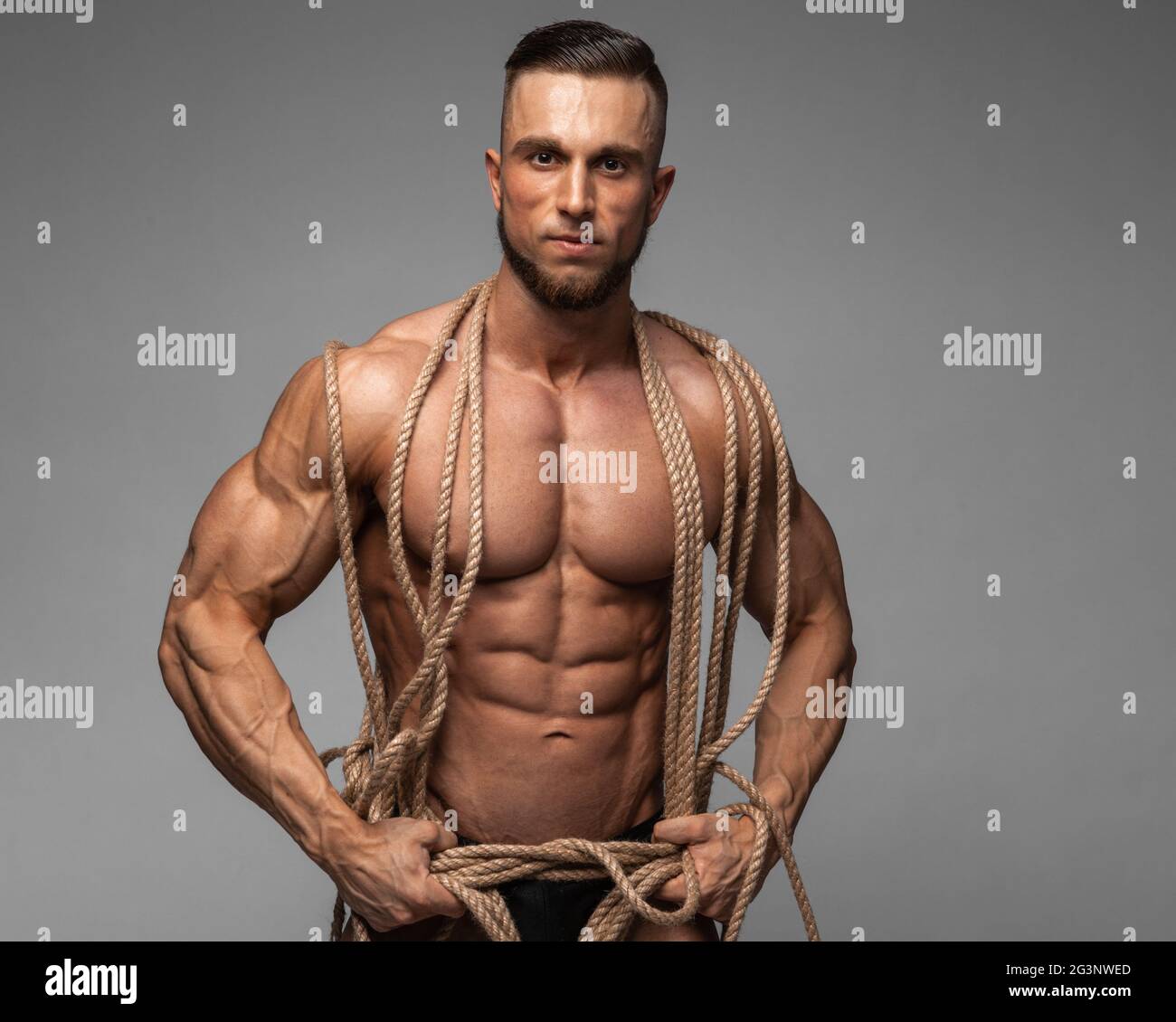 Starke muskulöse Männer gefangen in Seile, die versuchen, zu verlieren. Bodybuilder eingeschlossen in die Seile. Stockfoto