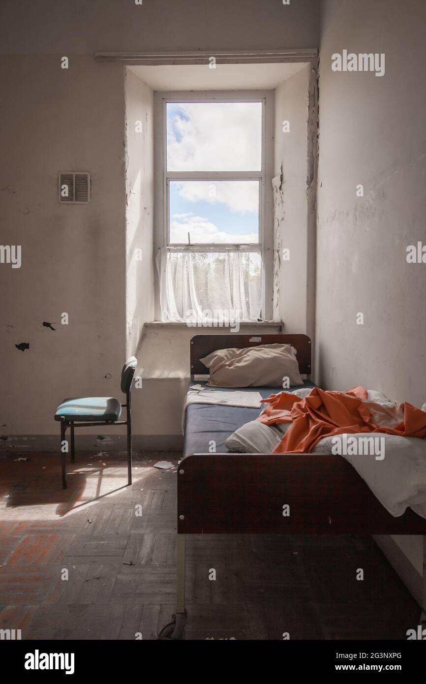 Ein Bett und ein Stuhl blieben in einem der alten Patientenzimmer. MIDLANDS, IRLAND: BETRETEN SIE EINES der BEUNRUHIGENDSTEN verlassenen Asyle Irlands? Abgeschlossen Stockfoto