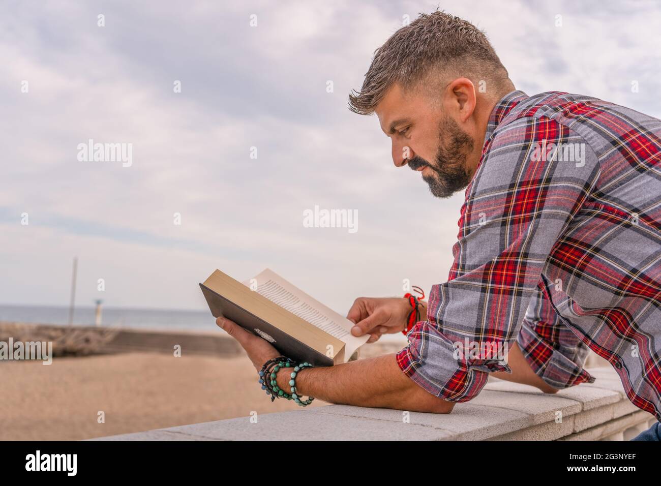 Nahaufnahme eines Mannes, der ein Buch über die Strandlandschaft las Stockfoto