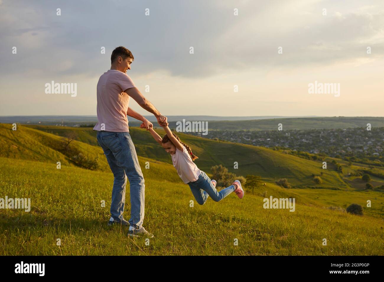 Sorgloser Vater und Tochter, die Spaß auf dem Hügel haben Stockfoto