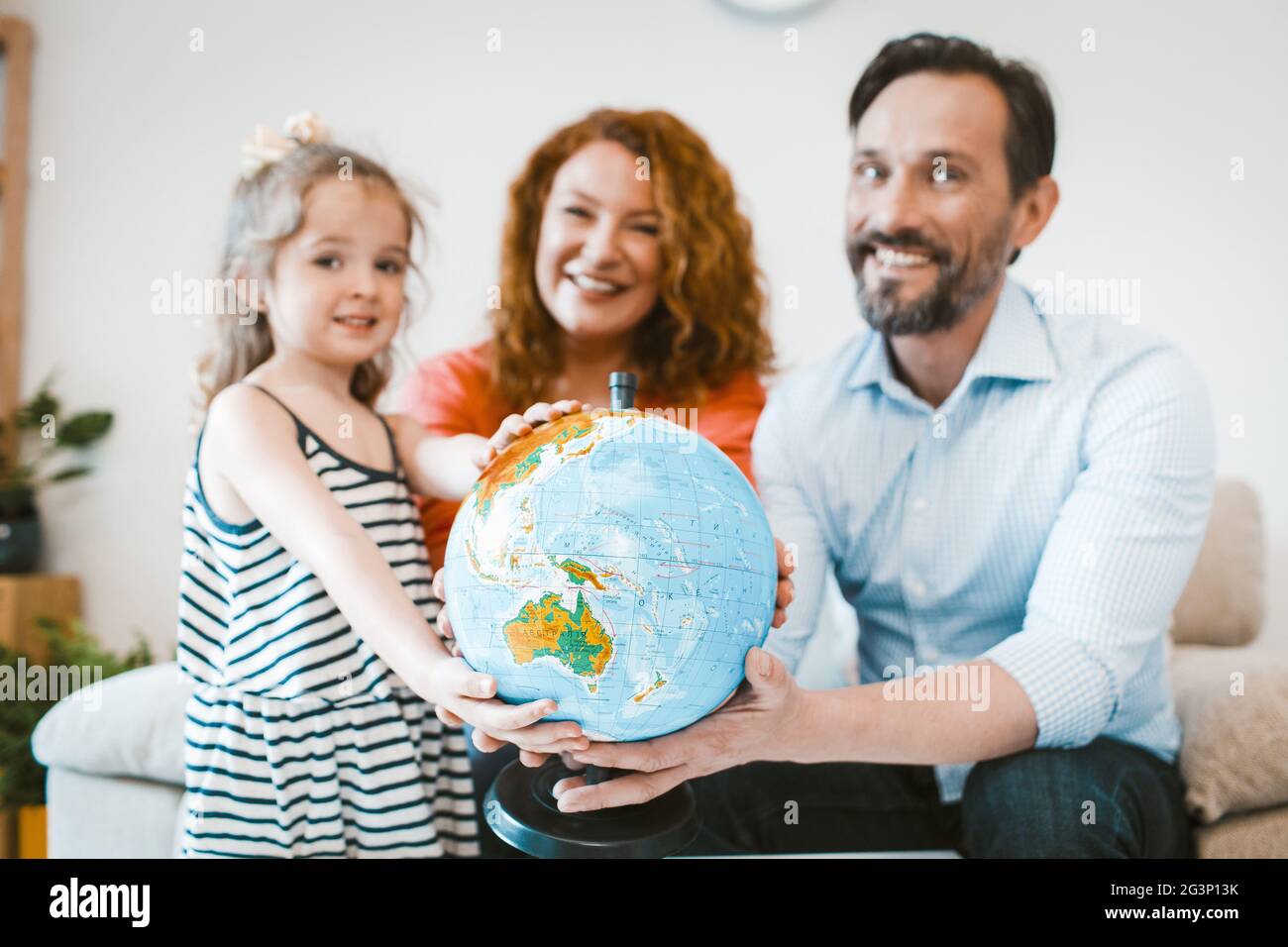 Mama, Papa und kleine Mädchen Planung Urlaub, holding Globe. Stockfoto