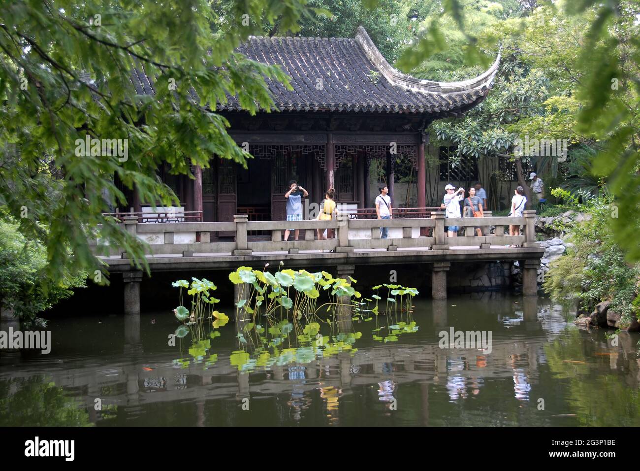 Yu Yuan Garten in der Altstadt von Shanghai, China. Ein traditioneller chinesischer Garten mit Bäumen, Felsen und Wasser. Menschen machen Fotos in der Nähe eines Pavillons. Stockfoto