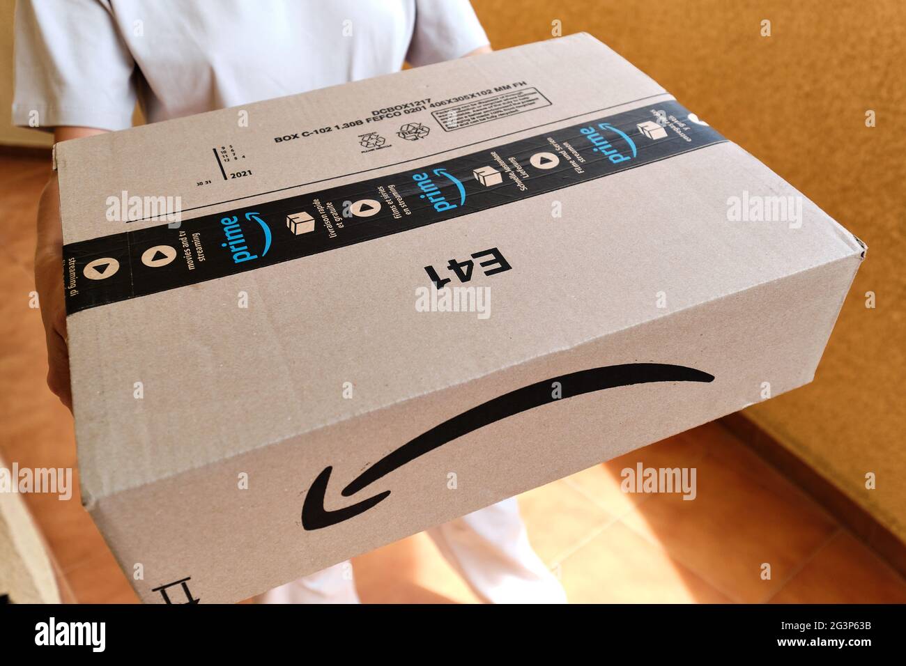 Spanien - 11. Juni 2021: Nahaufnahme beschnittene Ansicht Kurierhänden halten Amazon Premium Prime Karton Paketkasten, Logo Web kommerzielle Retail Services. E-comm Stockfoto