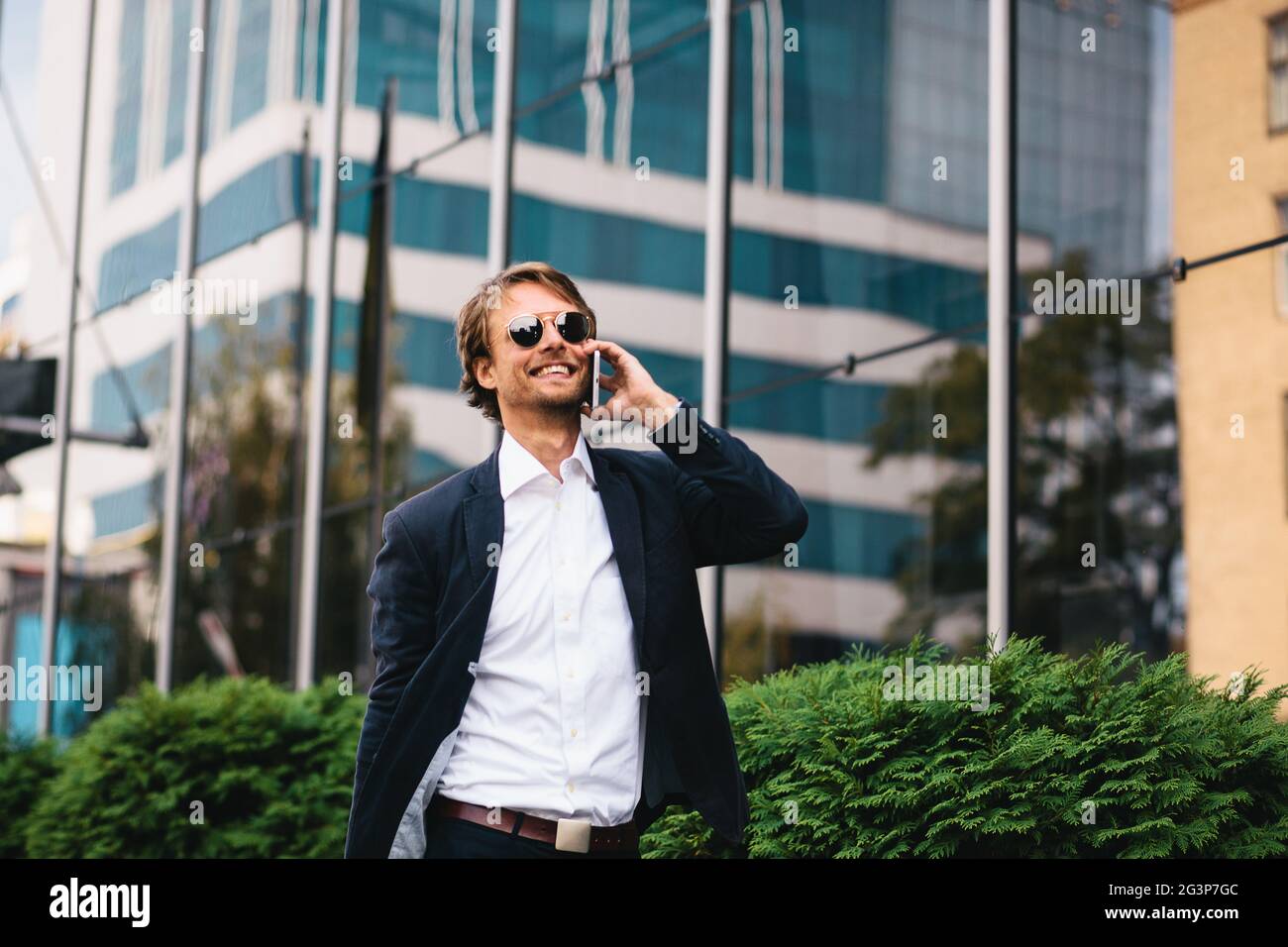 Der Geschäftsmann ging draußen für eine Pause, genießen Sie ein warmer Tag und Gespräch am Telefon mit einem Investor zu Stockfoto