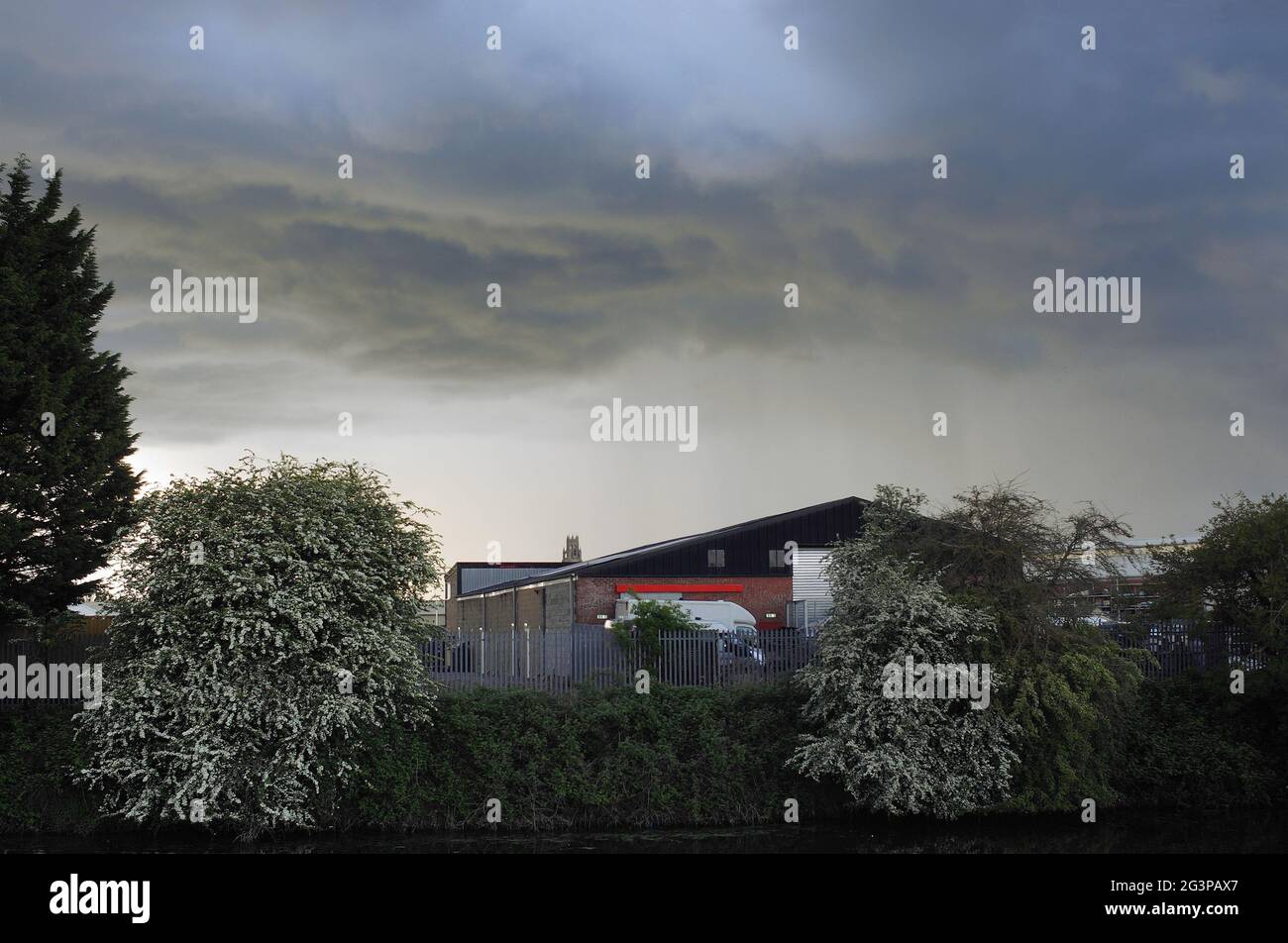 Dramatische Sturmwolken über einem Lagerhaus am Flussufer Stockfoto