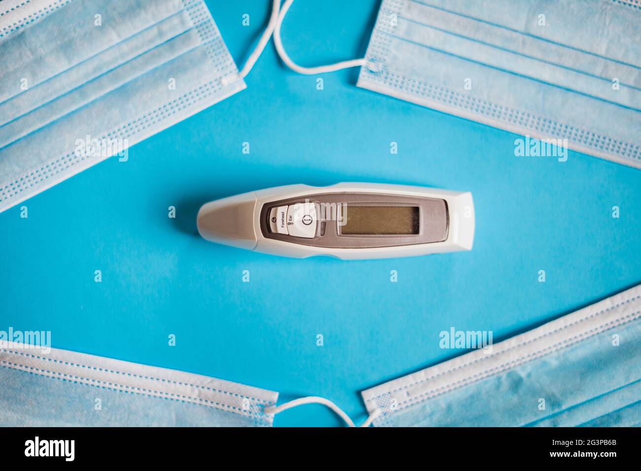 Ein Thermometer, das von vier chirurgischen Masken umgeben ist. Corona-Virenschutz. Stockfoto