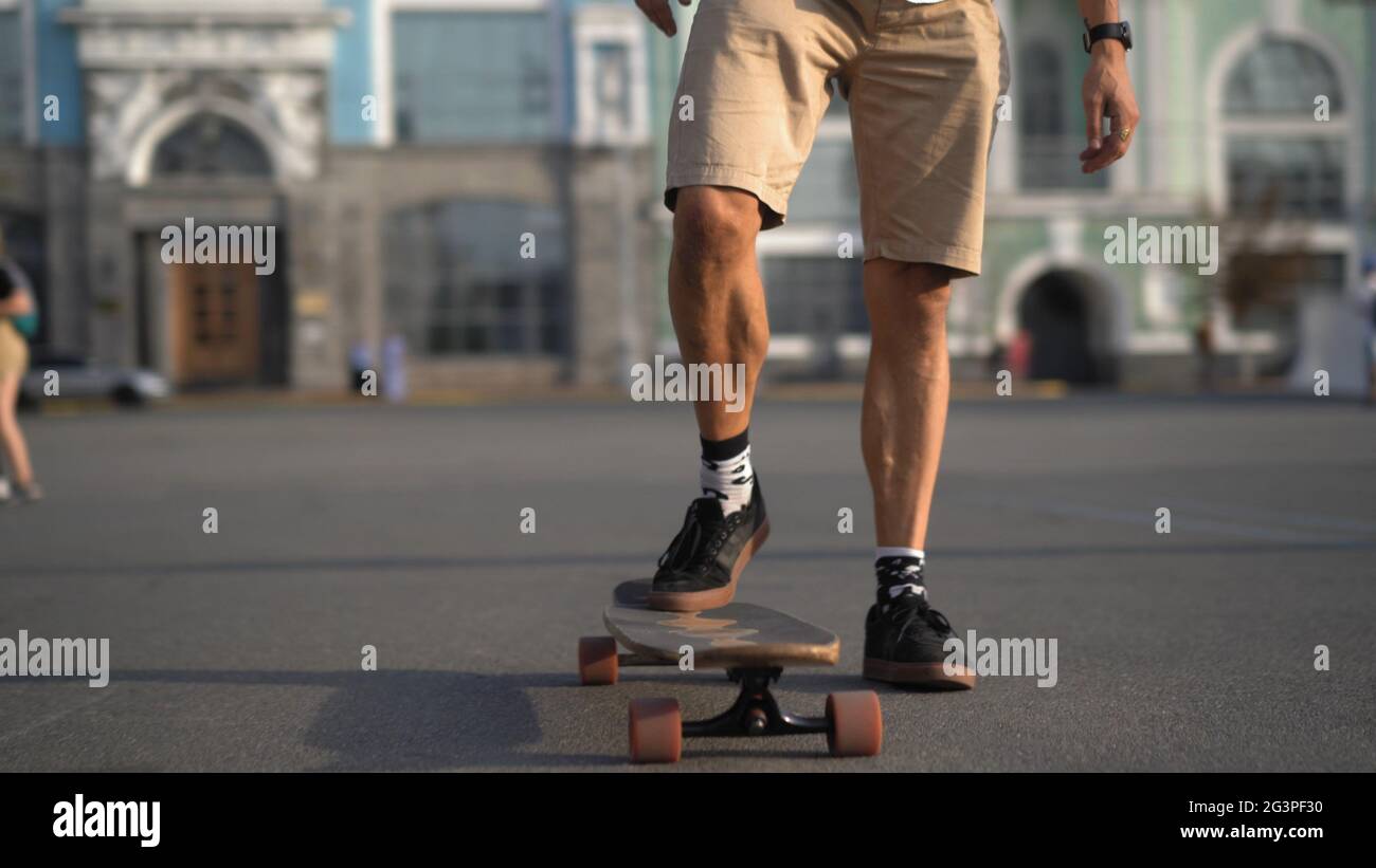 Die Füße der Männer bewegen sich auf einem Longboard im Freien. Stockfoto