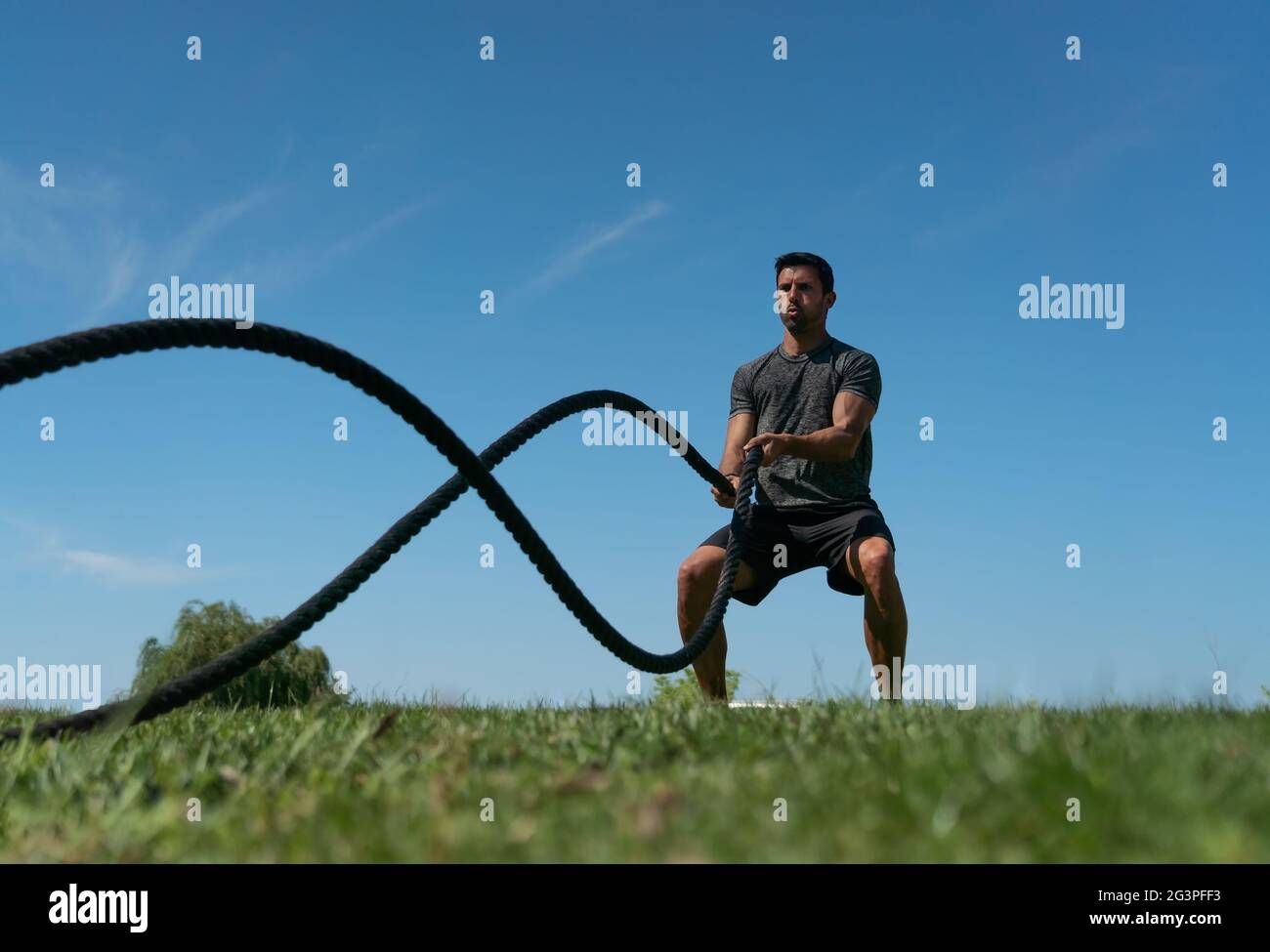 Männlicher Athlet im Freien im Park, Übungen für Ausdauer, mit einem dicken Seil, für Cross-Fitness. Europäisch Stockfoto