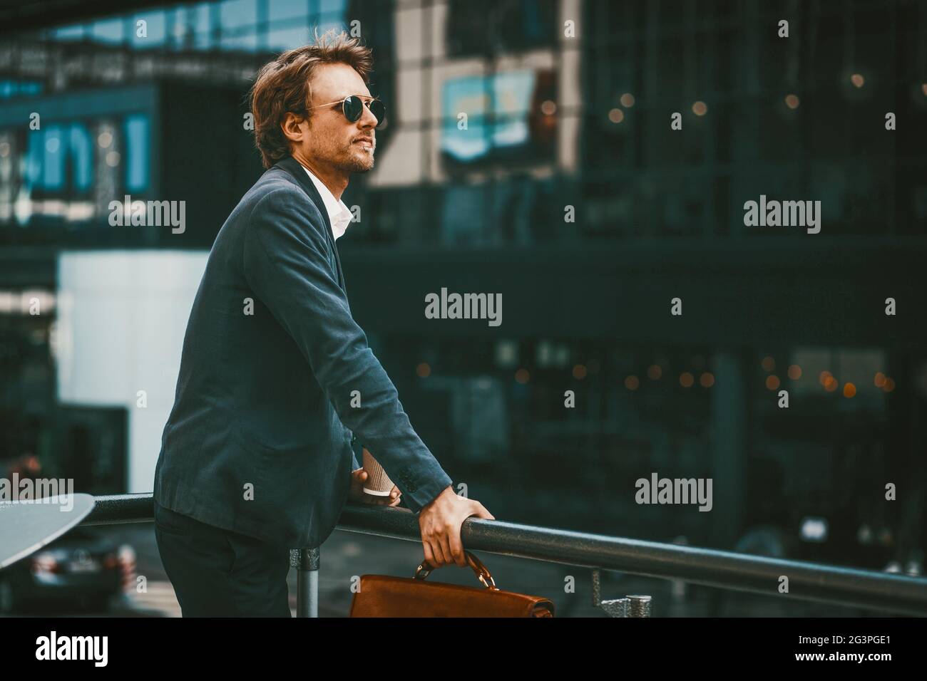 Geschäftsmann, der in einer blauen Sute an der frischen Luft neben dem Business Center steht Stockfoto