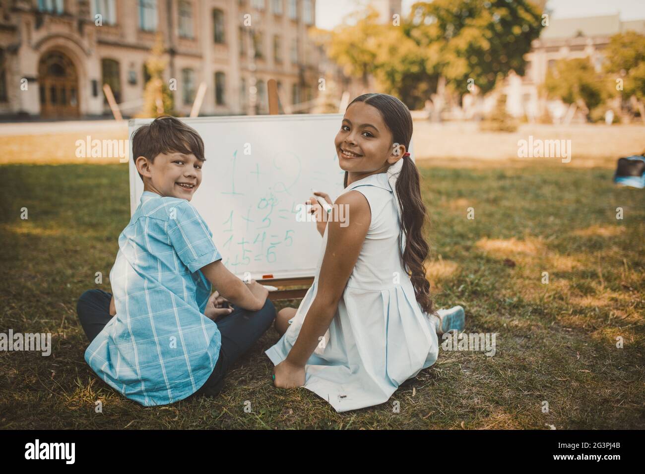 Fröhliche Kinder schreiben Zahlen auf Whiteboard in der Natur Stockfoto