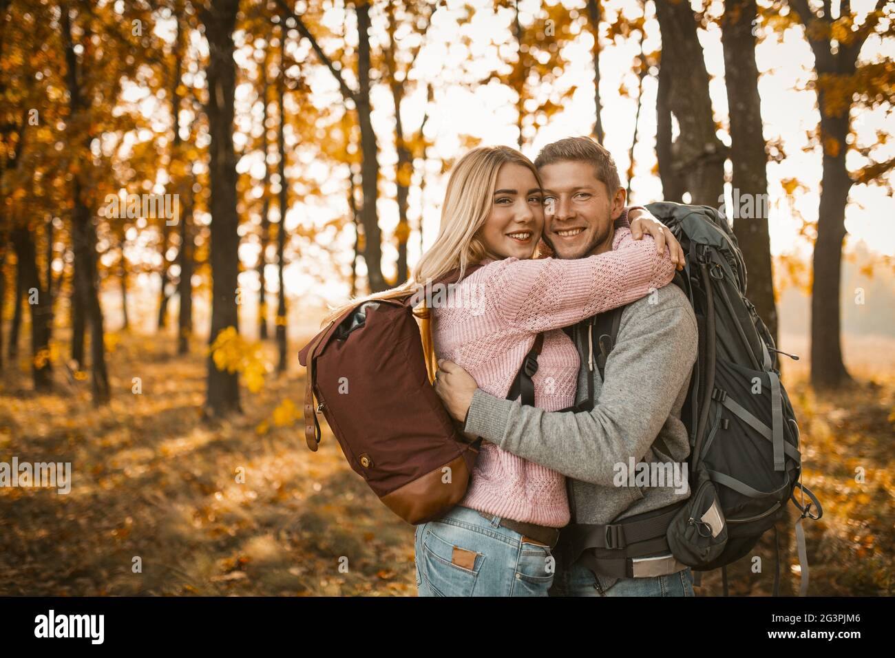 Junges, fröhliches Paar umarmt sich im Herbstwald Stockfoto