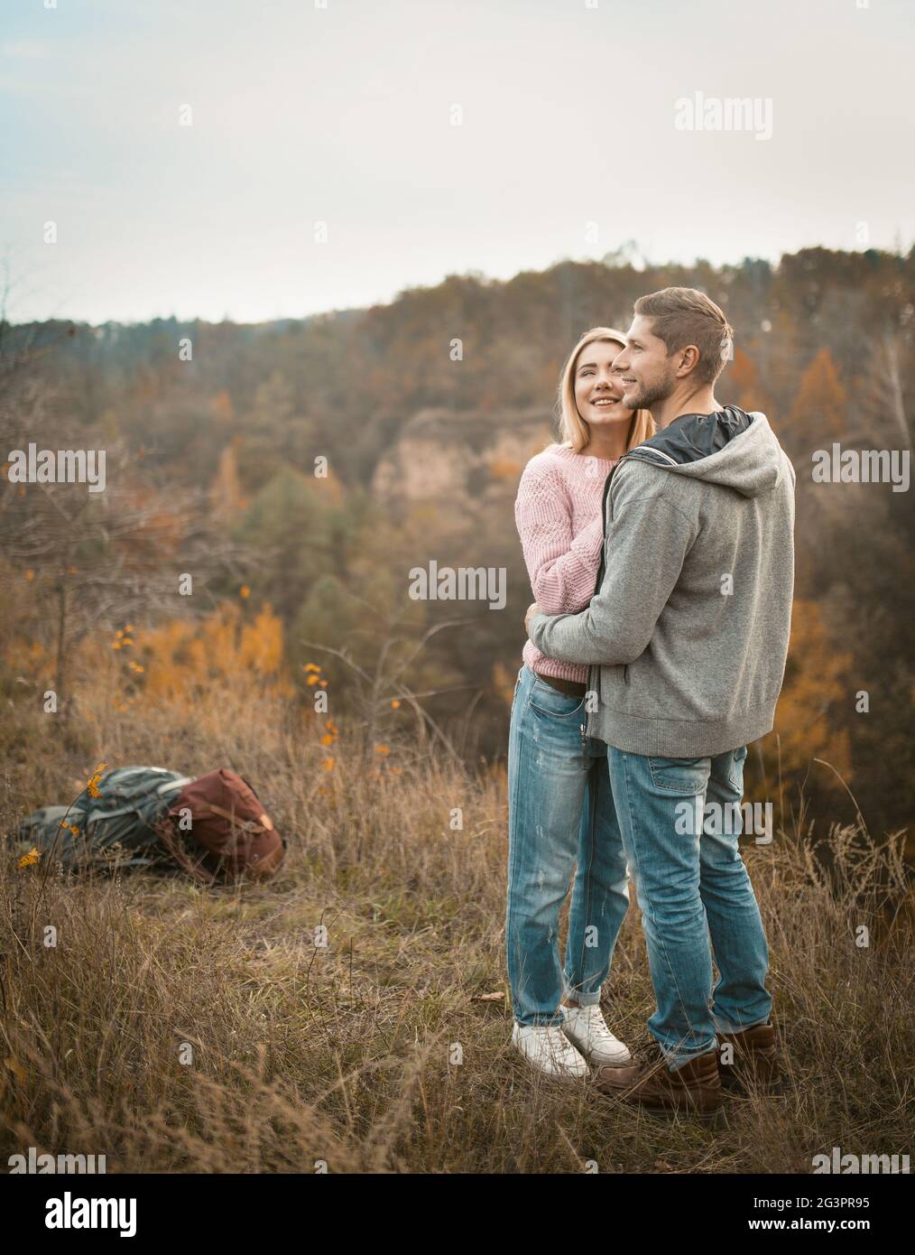 Junge Touristen stehen umarmt am Rande einer Klippe und inhalieren die Aromen der herbstlichen Natur Stockfoto