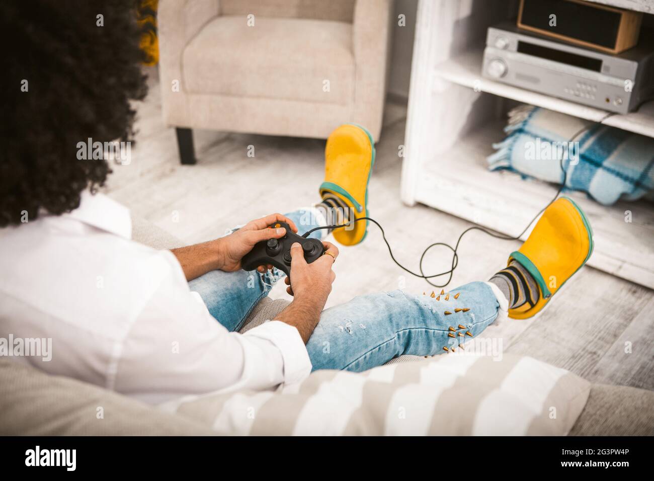Junger Mann spielt Computerspiel. Gamer Entferne die Tasten auf dem Joystick von der PlayStation im gemütlichen Innenraum. Mann in cas Stockfoto