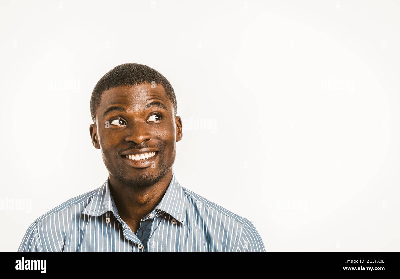 Lächelnder afroamerikanischer Mann schaut spielerisch zur Seite. Junger Geschäftsmann mit Kopierfläche auf der rechten Seite. Gesunde Zähne konz Stockfoto
