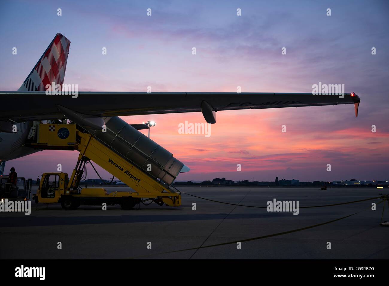 Ein Verkehrsflugzeug, das bei einem atemberaubenden Sonnenuntergang die Passagiere vom Flughafen Verona an Bord nehmen kann. Stockfoto