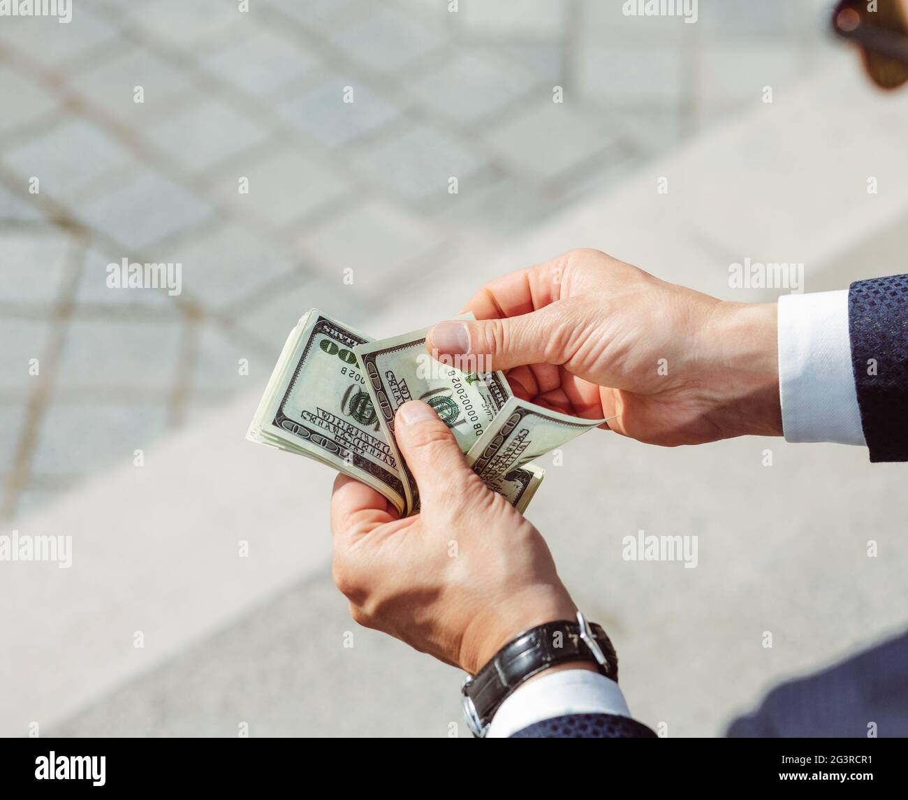 Die Hände der Männer halten Dollar. Erfolgreicher Geschäftsmann hält Gehalt.männliche Arme mit Uhr, Nahaufnahme. Hochwertige Fotos Stockfoto