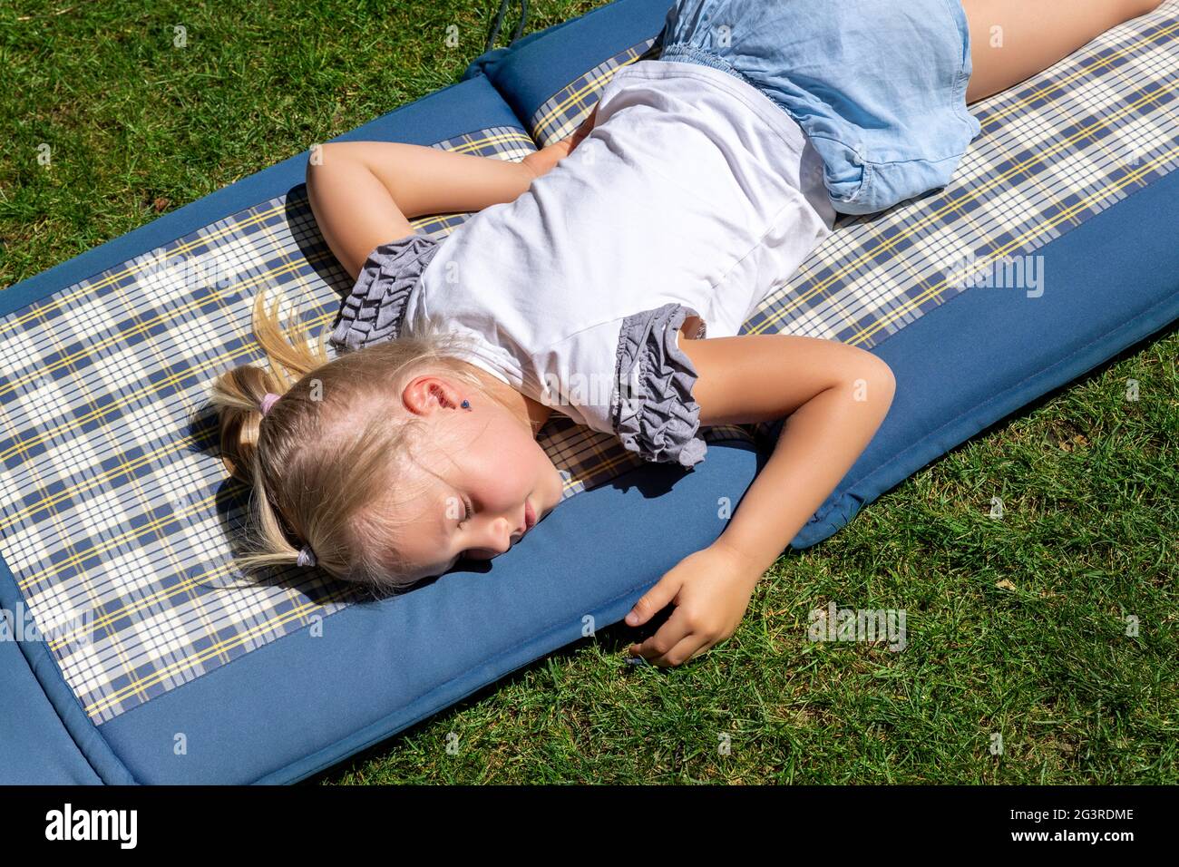 Niedliche liebenswert kaukasischen kleinen Schule Mädchen nappen und Tagträumen schlafen auf Matratze Matte über grünem Rasen im Garten zu Hause liegen. Gesundheit von Kindern Stockfoto