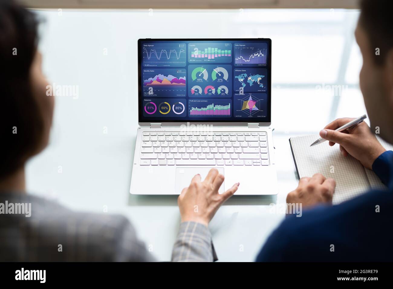 Zwei Analytiker, die KPI-Dashboard auf einem Laptop verwenden Stockfoto