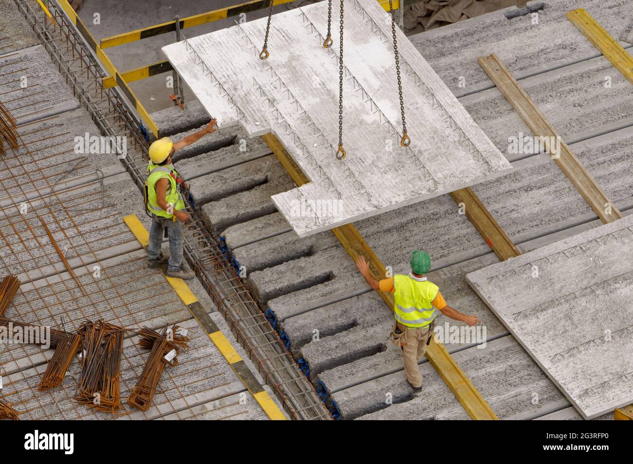 Arbeiter auf einer Baustelle, die die Betonplatte von einem großen Kran gelenkt hat Stockfoto