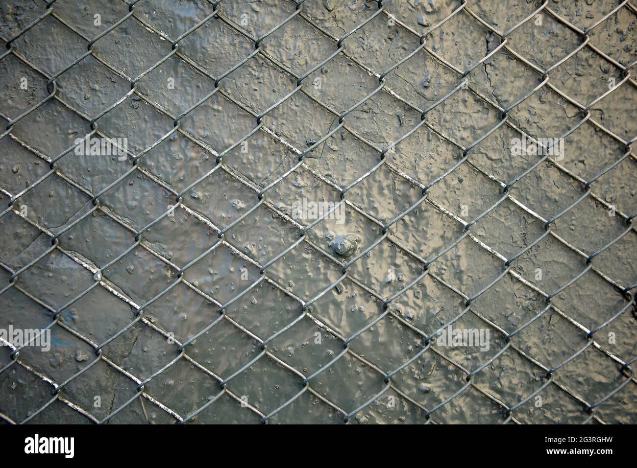 Die Textur der grau lackierten Wand ist mit Stahldrahtgeflecht verstärkt. Stockfoto