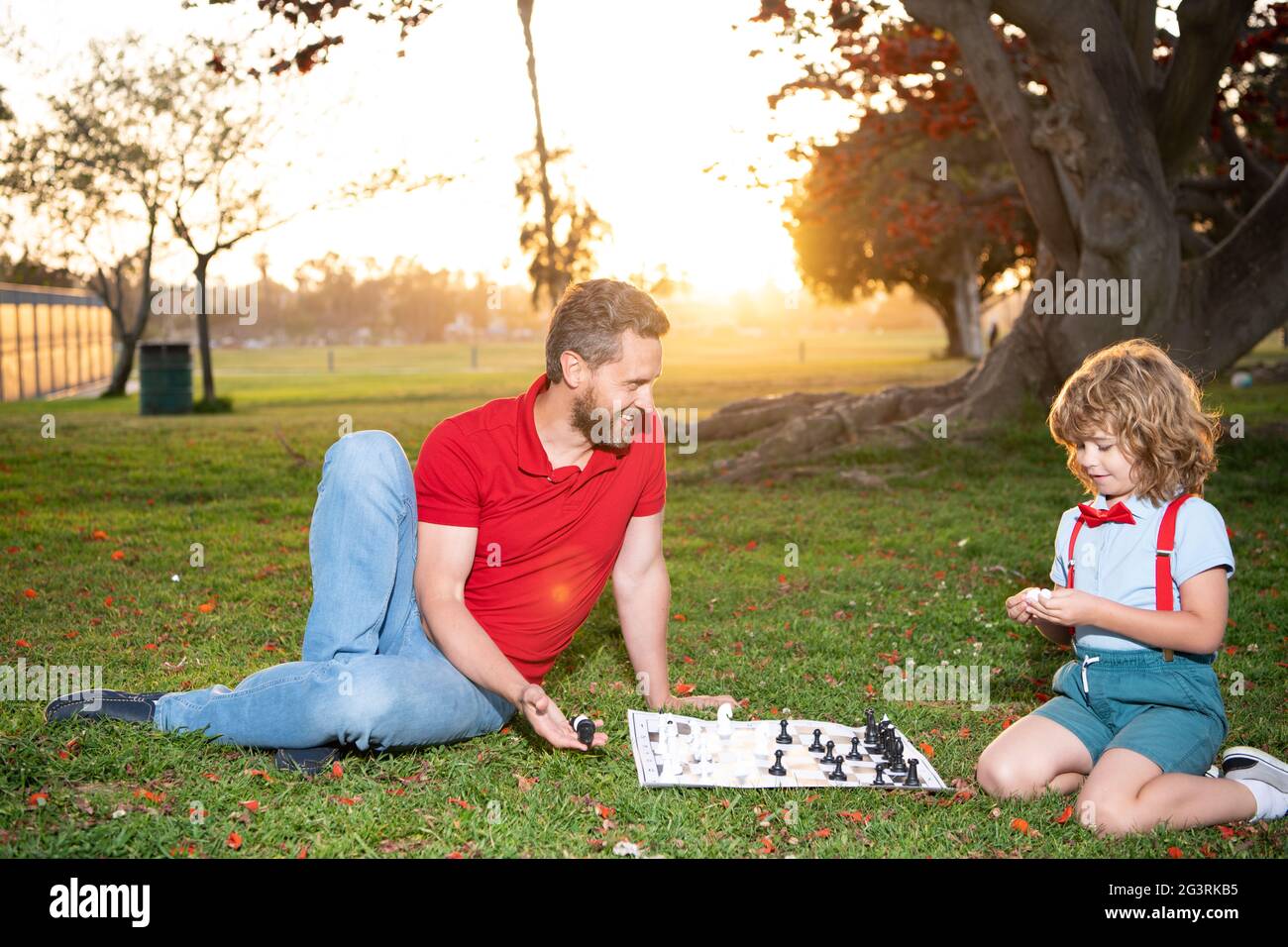 Vater und Sohn spielen Schach auf Gras im Sommerpark, Vaterschaft Stockfoto