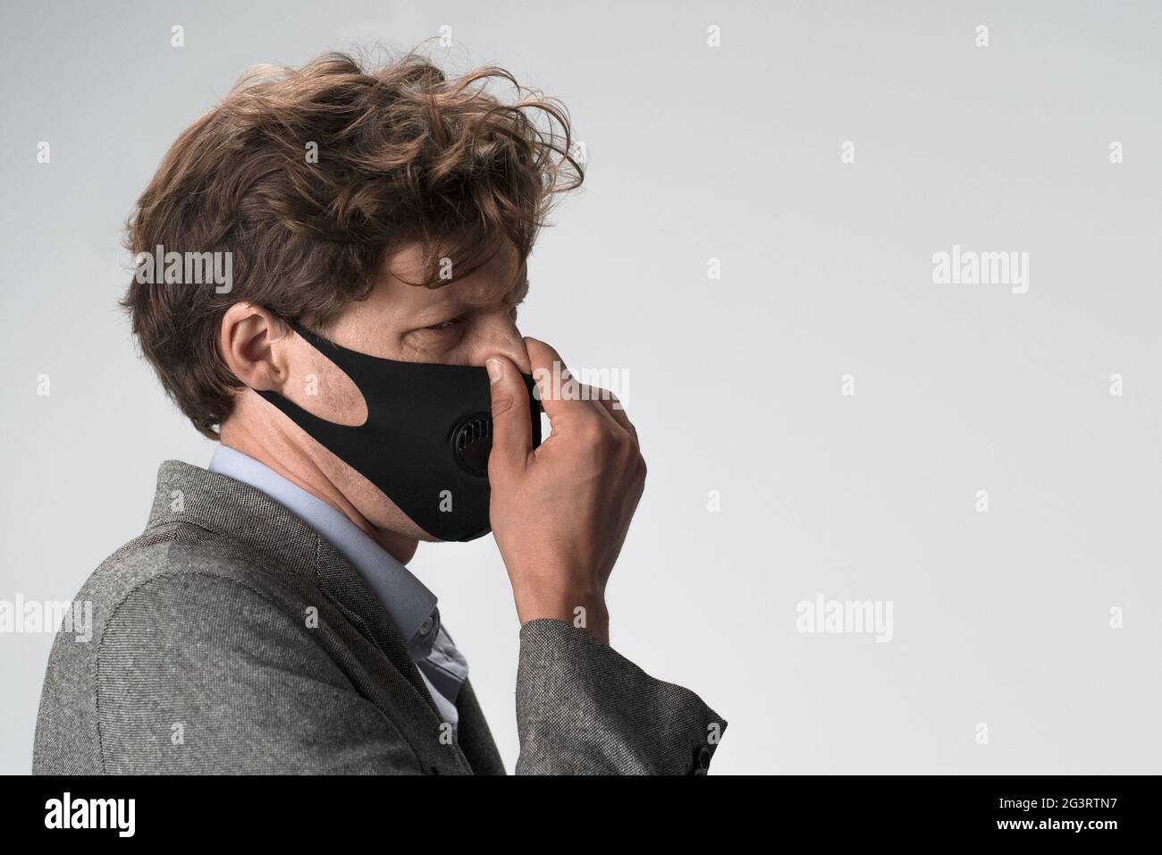 Kaukasischer Mann in Schutzmaske Winzen reiben seine Nase. Profilansicht. Nahaufnahme Stockfoto