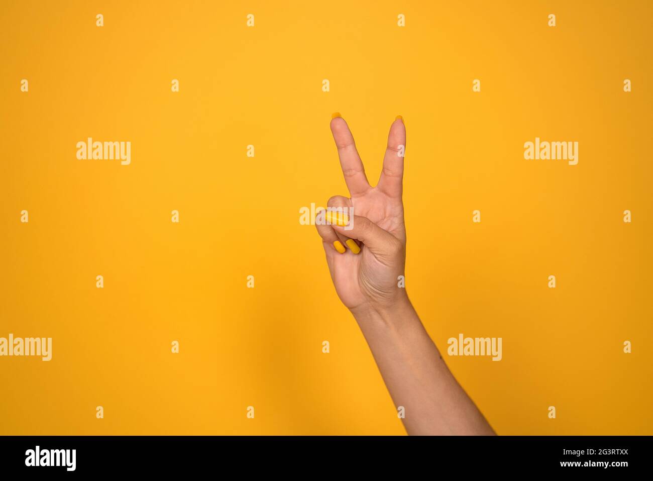 V-Zeichen. Weibliche Hand zeigt zwei Finger oder Friedensgeste. Auf gelbem Hintergrund ausschneiden. Speicherplatz kopieren Stockfoto